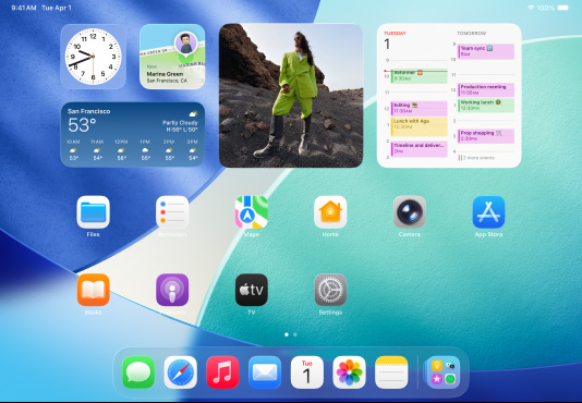 Kolme iPad-mallia vaaka-asennossa, keskimmäinen kahden muun edessä, Apple Pencil kiinnitettynä magneettisesti keskimmäisen mallin yläosaan. Keskimmäinen näyttö vaihtuu lukitusta näytöstä Koti-valikkoon, jossa näkyy värikkäitä appikuvakkeita Liquid Glass ‑ulkoasulla. Vasemmassa näytössä näkyy Esikatselu-appi, oikeassa näytössä näkyy Koti-valikko ja Dockista viuhkamaisesti lähteviä tiedostoja