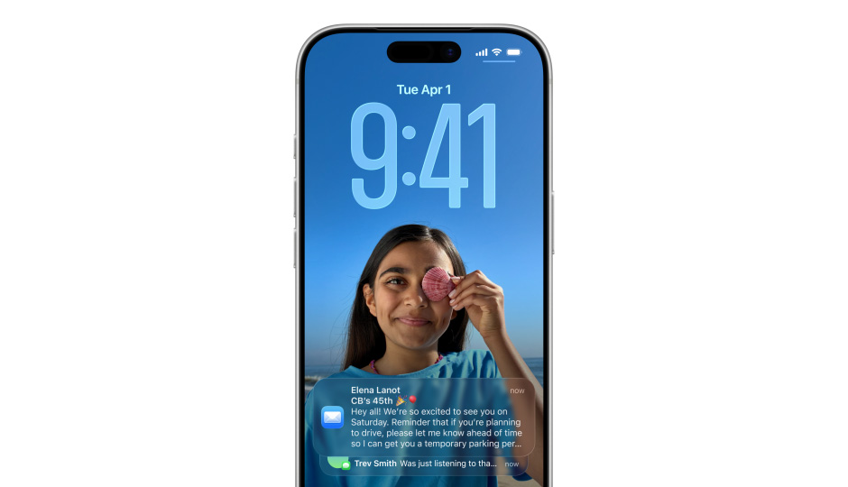Egy iPhone zárolási képernyője egy fotóval és az időt jelző Liquid Glass-megjelenésű számokkal. A képernyő alján két értesítés jelenik meg