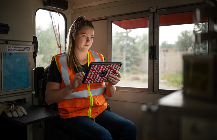 Une cheminote est assise dans un wagon à l’arrêt et consulte un iPad