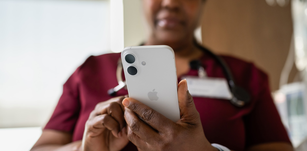 Nữ y tá mặc đồng phục y tế màu đỏ đang nhìn vào iPhone.