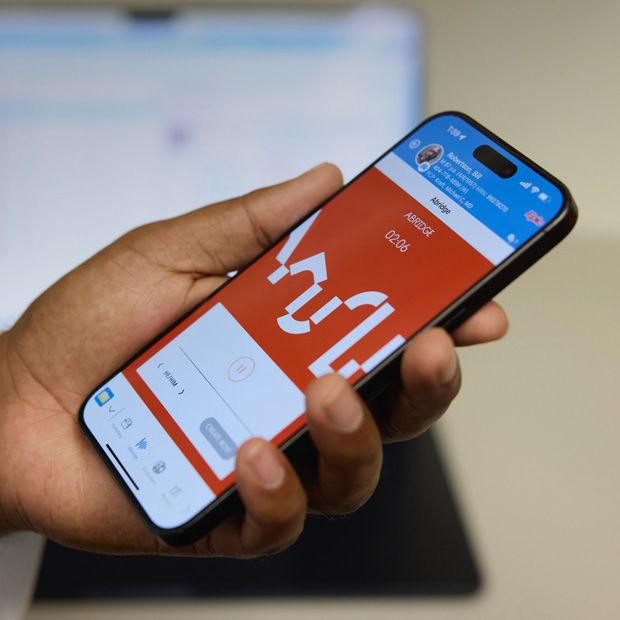Bàn tay cầm iPhone hiển thị ứng dụng Abridge, giúp chuyển ngữ các trao đổi giữa bệnh nhân và bác sĩ  thành  ghi chú lâm sàng.